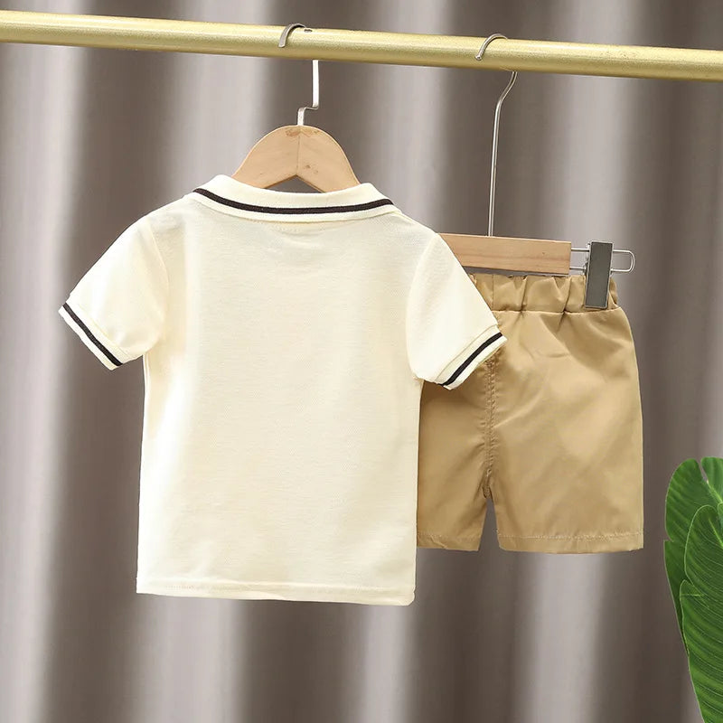 Baby boy summer outfit with beige shorts and white short-sleeve polo shirt on hangers