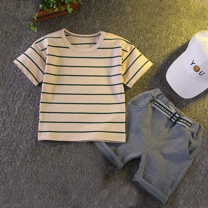Striped short-sleeve baby t-shirt with gray shorts and white cap on gray background.