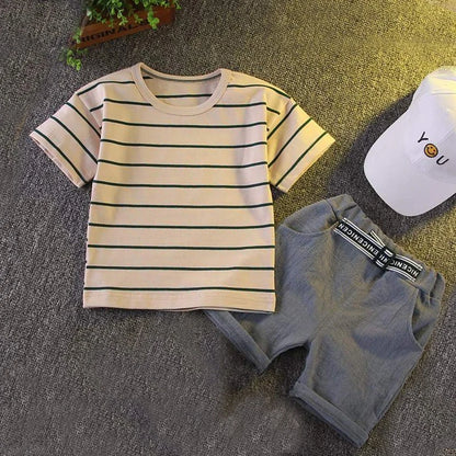 Striped short-sleeve baby t-shirt with gray shorts and white cap on gray background.