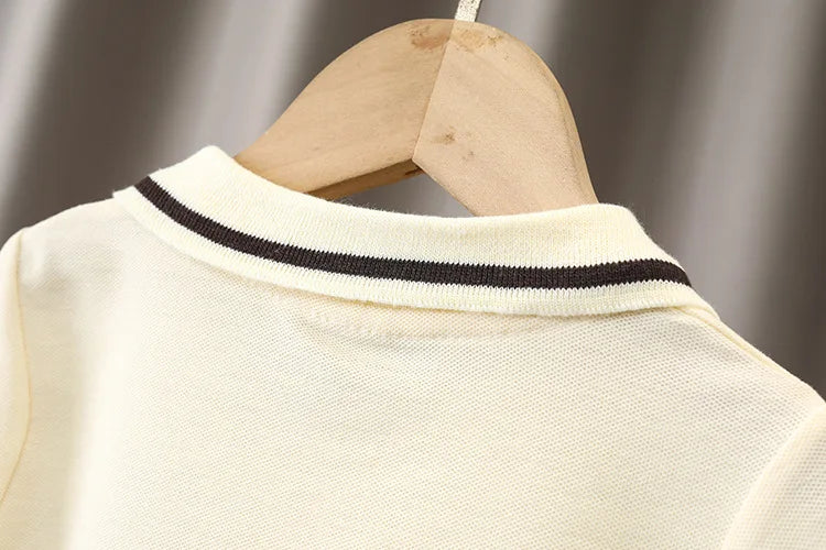 Detail of cream baby shirt with black striped collar on wooden hanger