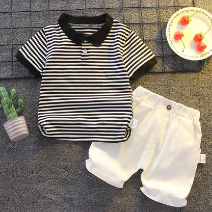 Striped baby boy polo shirt and white shorts set, summer infant outfit flat lay.