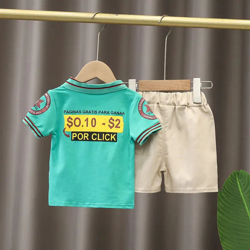 Kids summer outfit with green graphic t-shirt and beige shorts hanging on rack